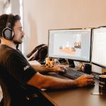 Profissional trabalha em um computador com dois monitores em um escritório moderno.