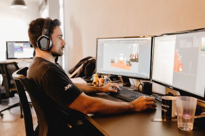 Profissional trabalha em um computador com dois monitores em um escritório moderno.