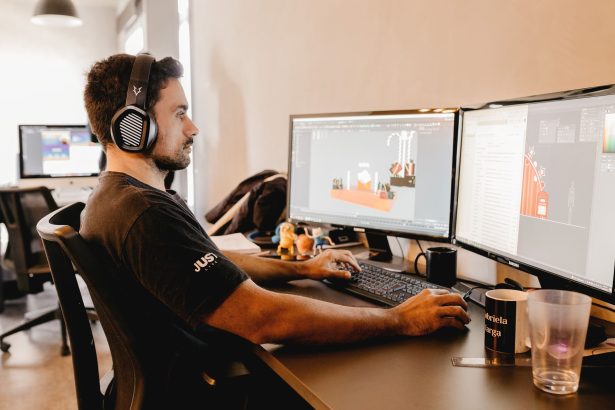 Profissional trabalha em um computador com dois monitores em um escritório moderno.